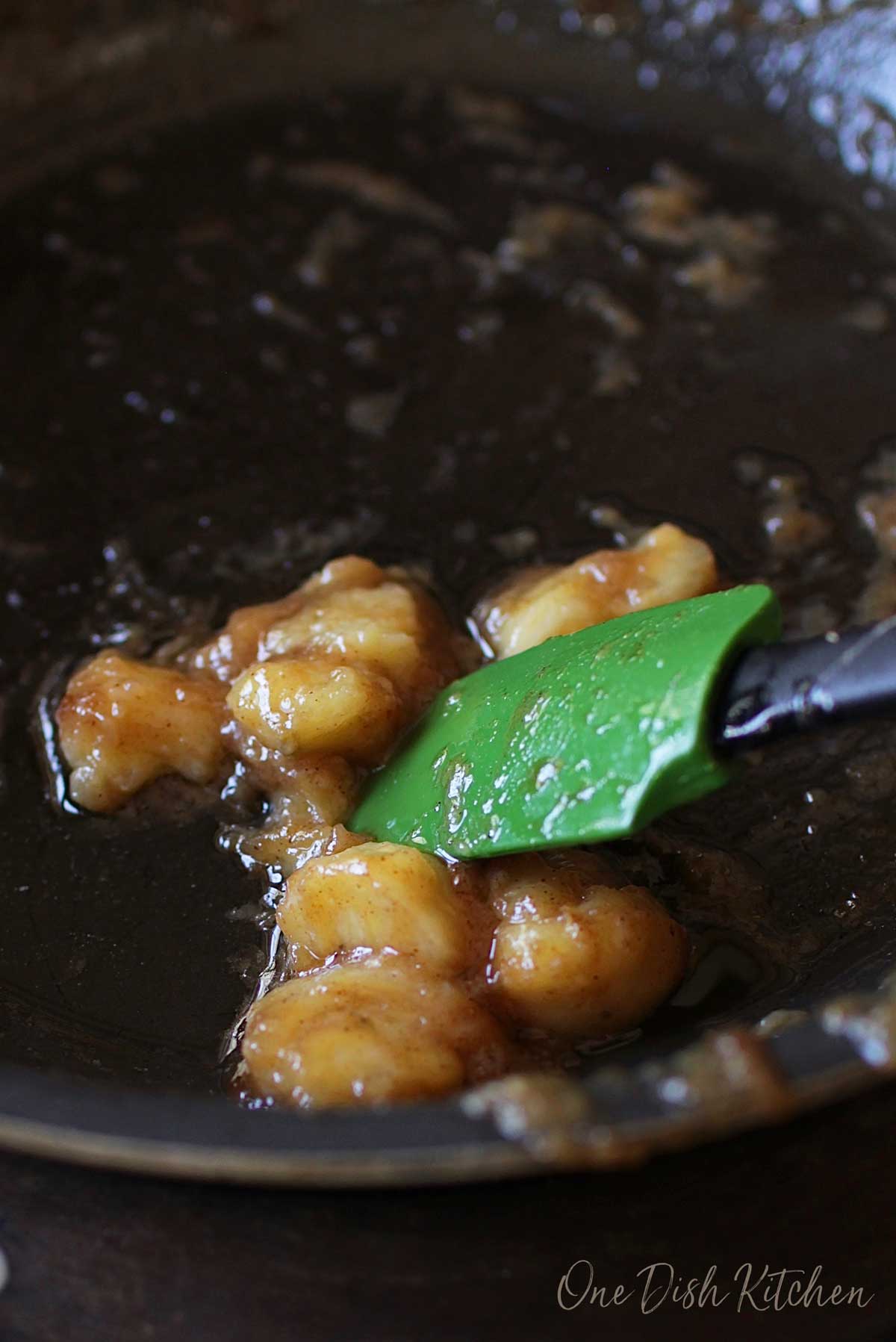 Banana slices cooking in a pan with melted butter and brown sugar.