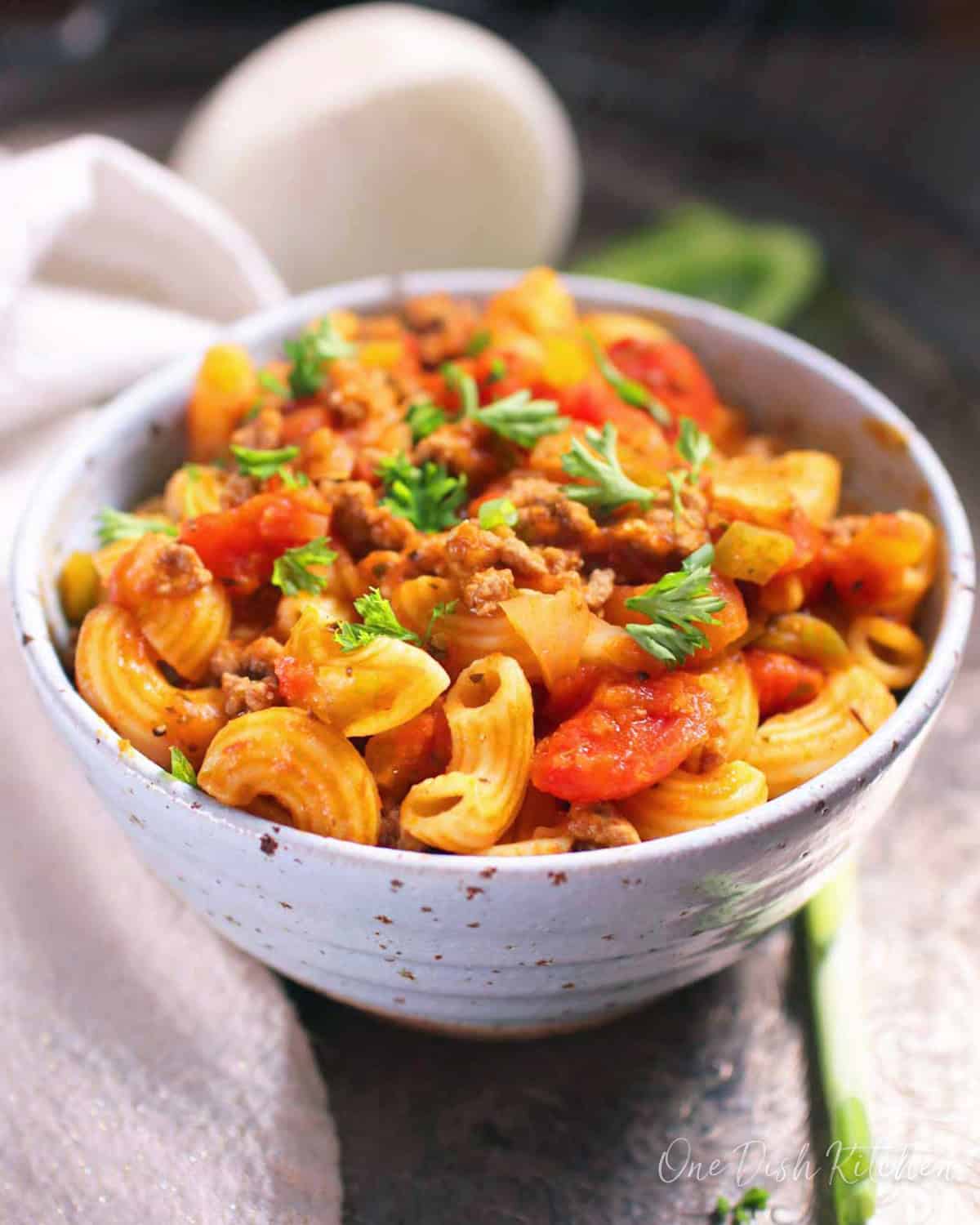 A bowl of american goulash topped with fresh parsley.