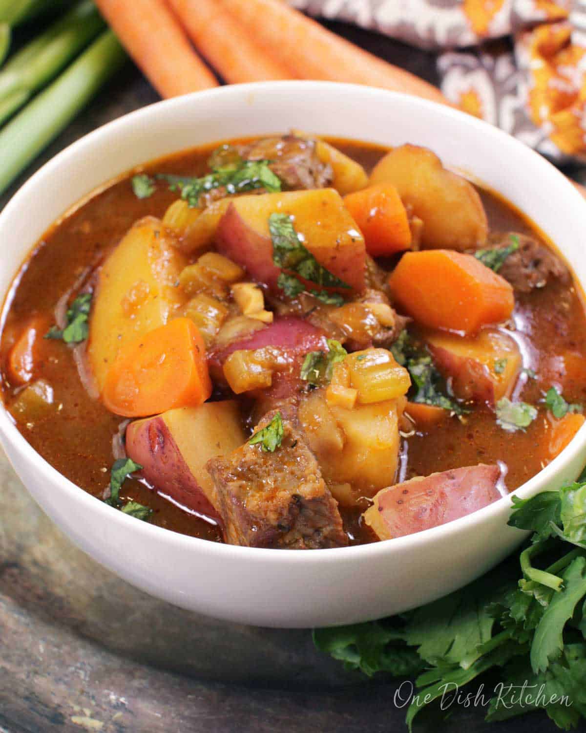 a single serving of irish stew in a bowl in a silver tray.
