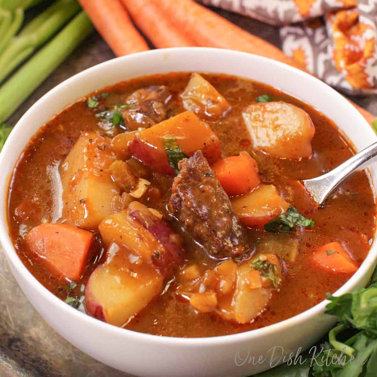 a small batch of guinness irish stew in a bowl with a spoon on the side.
