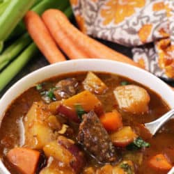 a bowl of stew filled with lamb, carrots and potatoes.