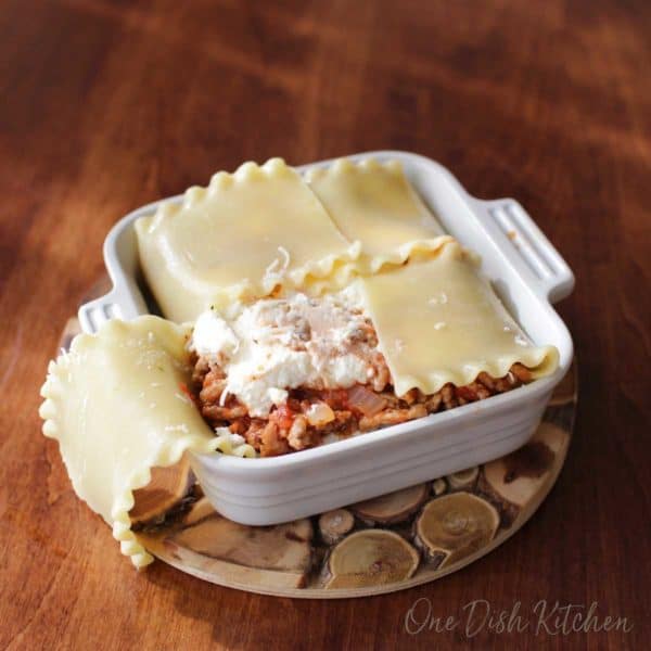lasagna filling of meat and cheese added to dish with noodles on bottom with some of noodles folded over top