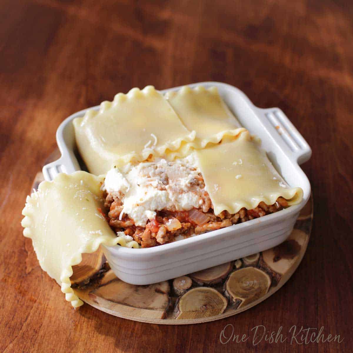 Adding the meat filling to a mini lasagna and folding the noodles over the mixture.