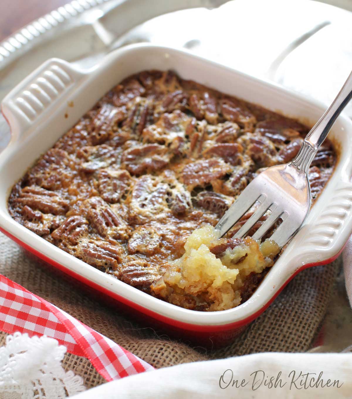 A forkful of pecan pie baked on a shortbread crust on a burlap cloth.