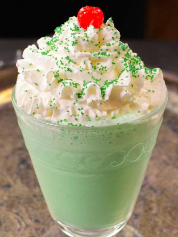 a single shamrock shake in a glass topped with whipped cream, a cherry and sprinkles.