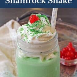 a shamrock shake in a mason jar topped with whipped cream and a cherry.