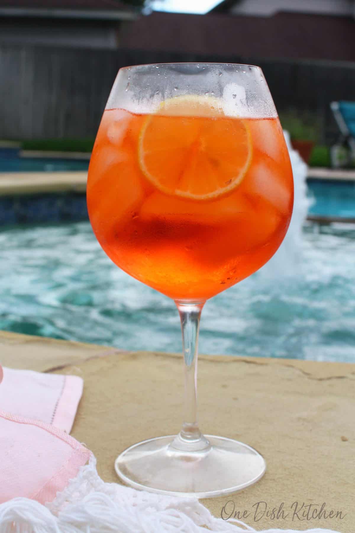An aperol spritz next to a swimming pool 