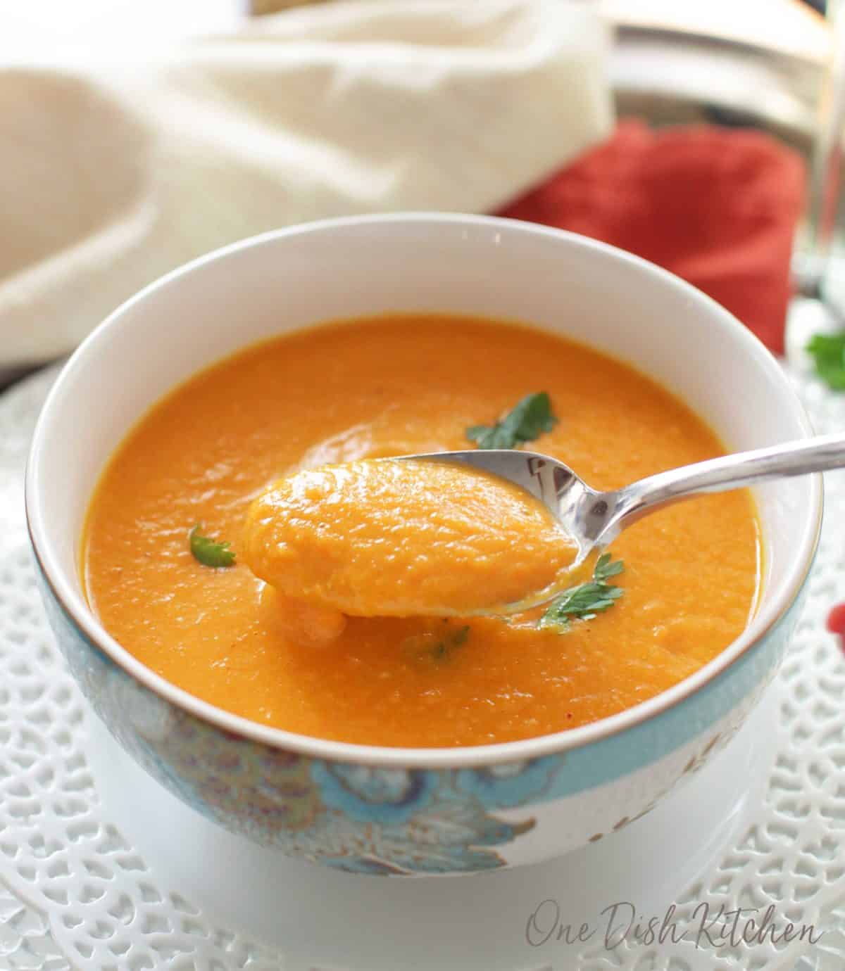 A closeup of a spoonful of carrot soup garnished with cilantro.