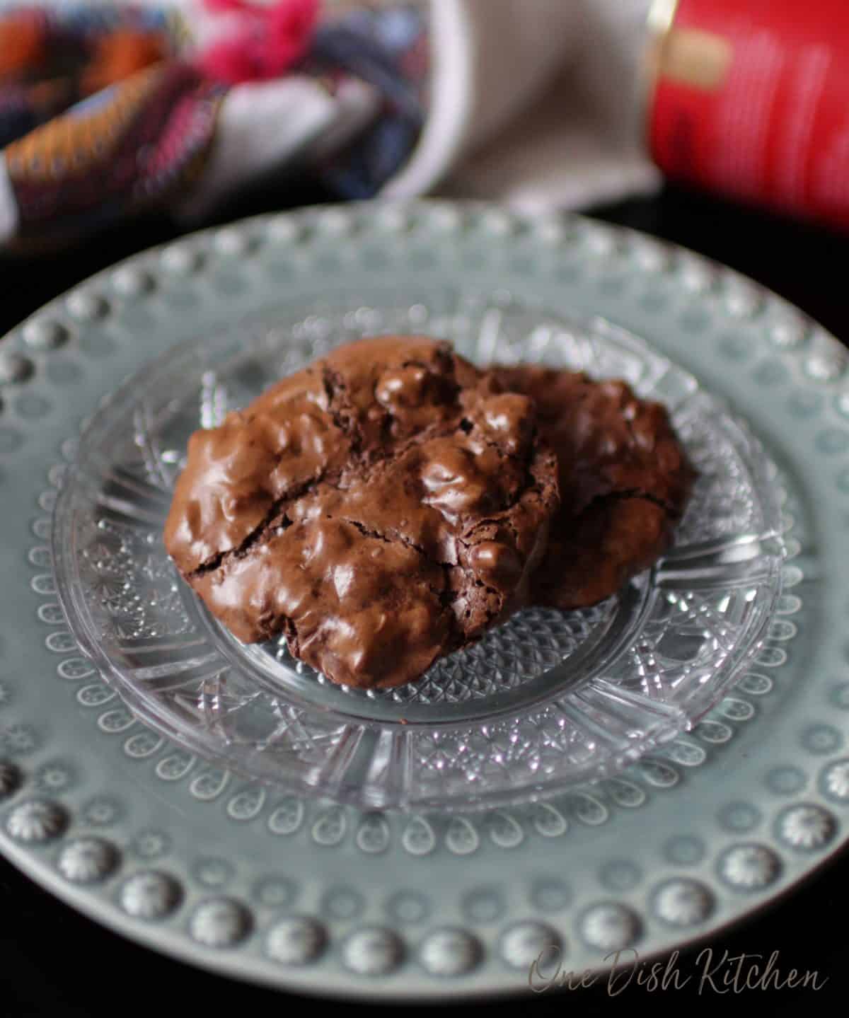 Two flourless chocolate cookies with pecans stacked on a plate 