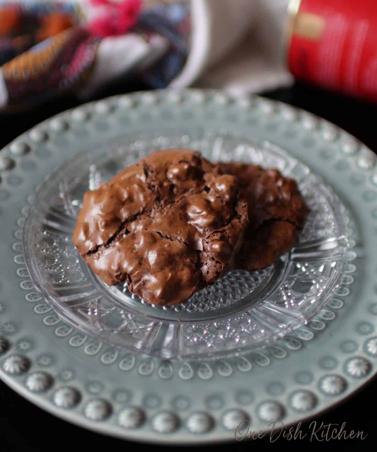 Two flourless chocolate cookies with pecans stacked on a plate.