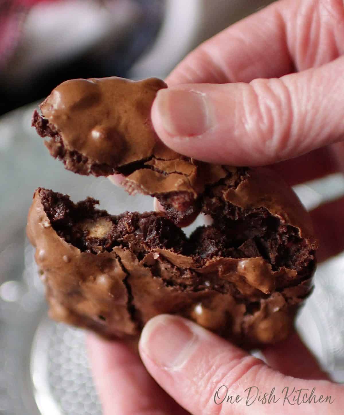 A closeup of a flourless chocolate cookie broken in half.