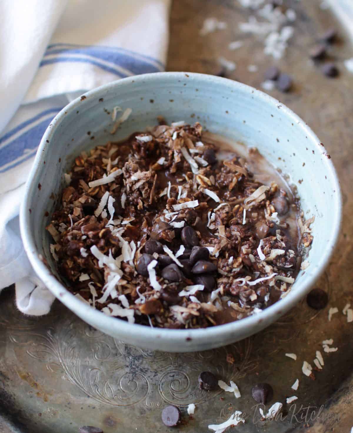 Oatmeal bowl made with chocolate and topped with coconut shavings on a metal