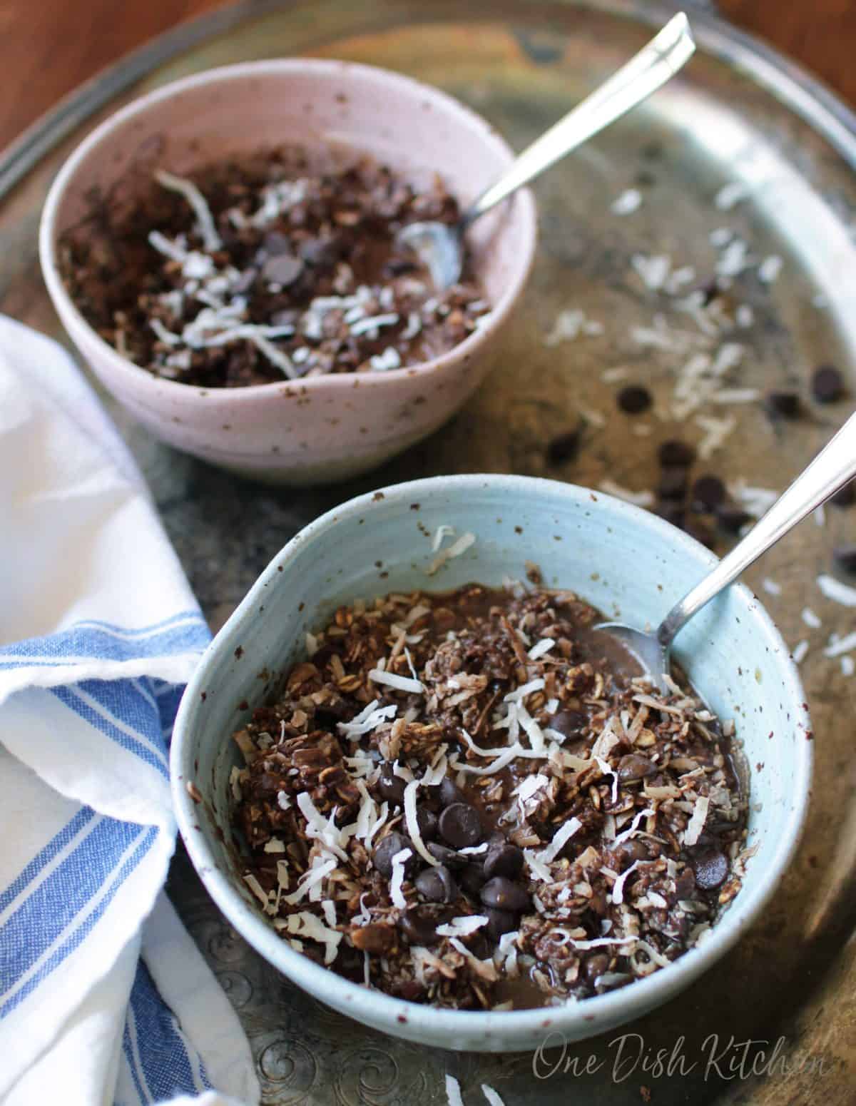 Two bowls of mocha oatmeal topped with coconut shavings on a metal tray