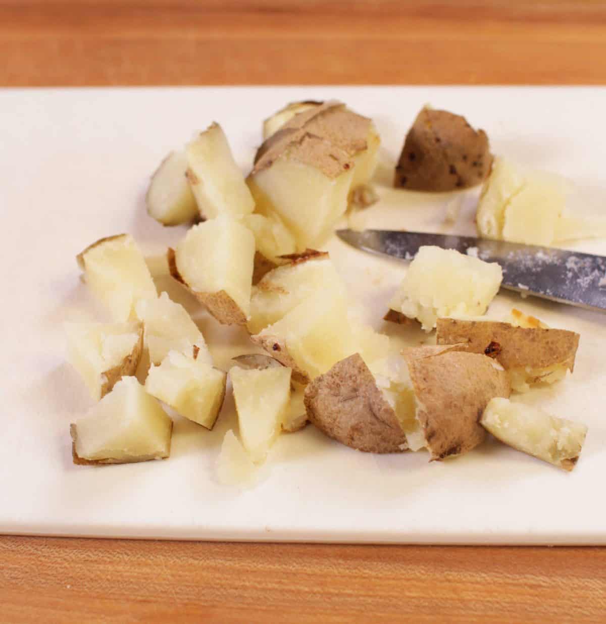 Russet potatoes cut up into one inch cubes on a cutting board 