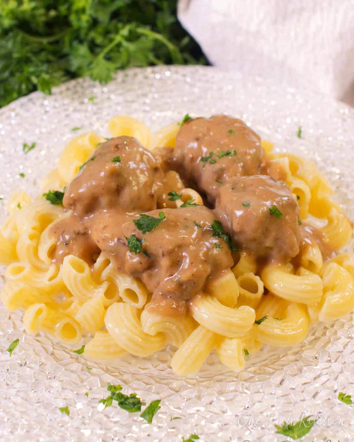 a single serving of swedish meatballs over pasta on a plate.