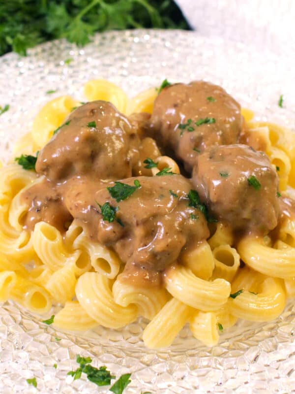 a plate of swedish meatballs and gravy over noodles.