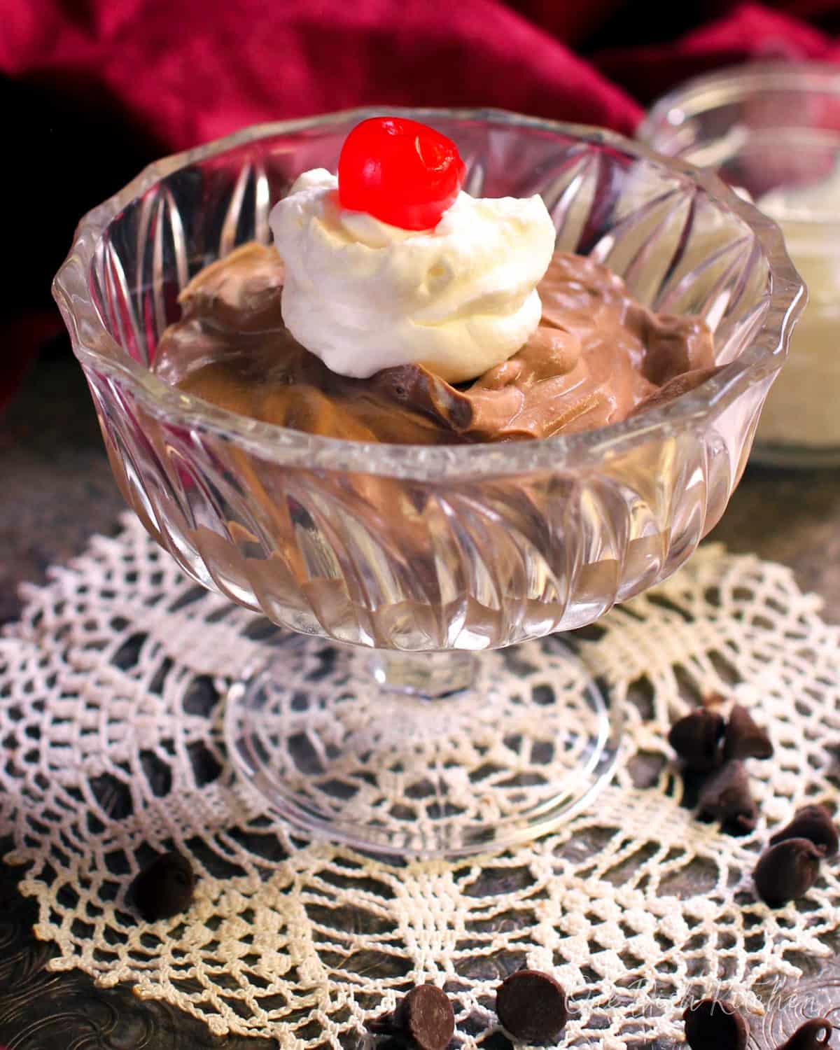 a bowl of chocolate mousse topped with whipped cream and a cherry.