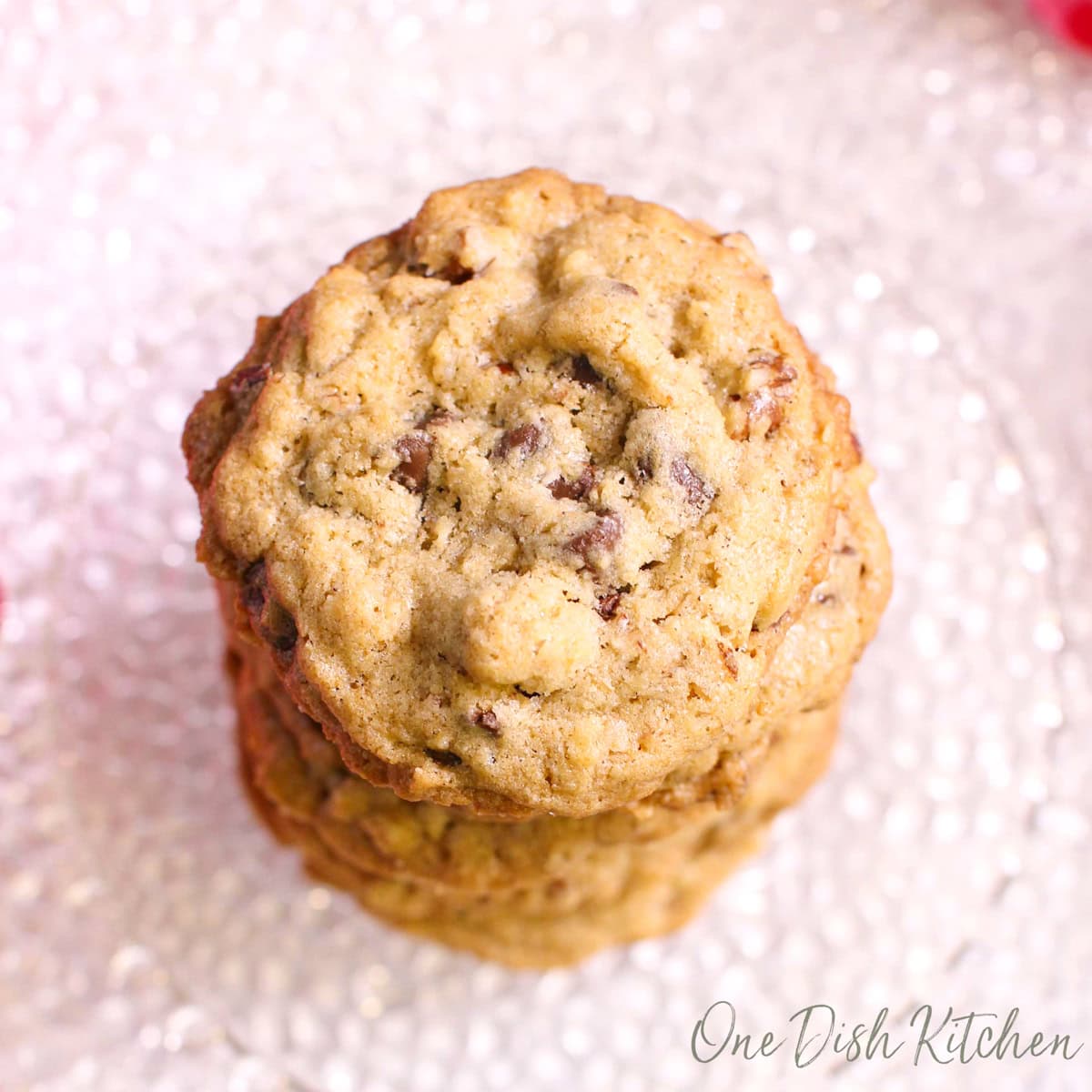Stacked DoubleTree chocolate chip cookies with oats, walnuts, and melted chocolate chips on a plate.
