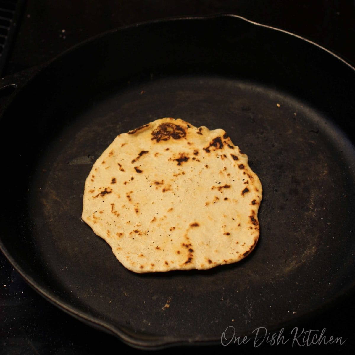 a browned tortilla in a black pan.