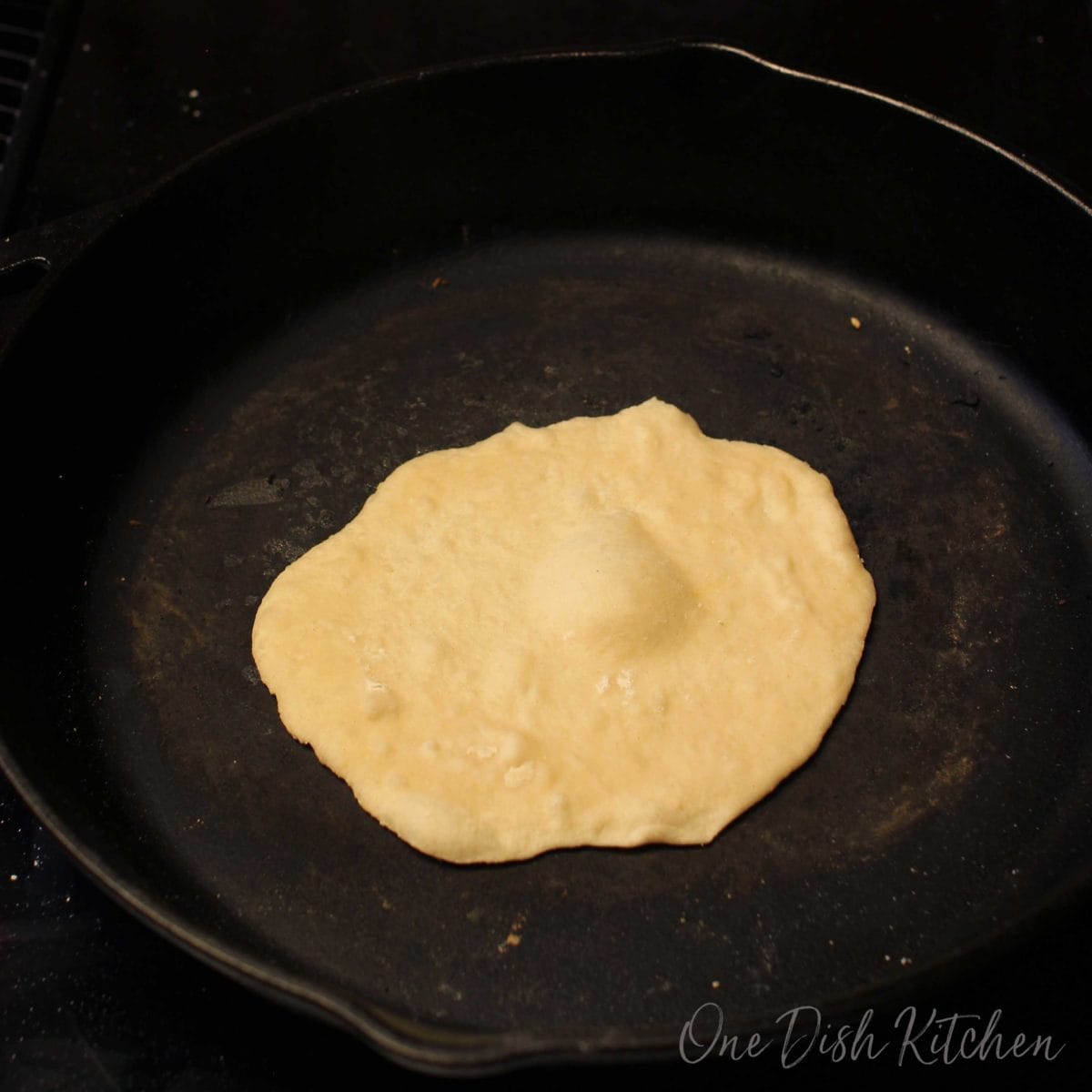 a tortilla heating in a skillet with a bubble rising up.