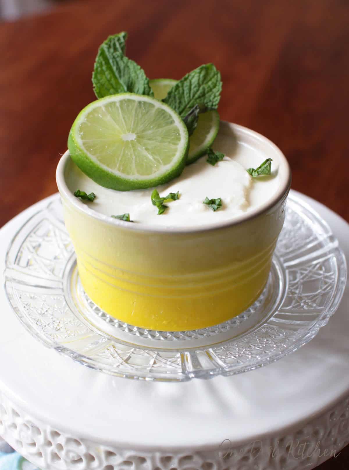 A lime posset dessert topped with two lime wheels and mint leaves