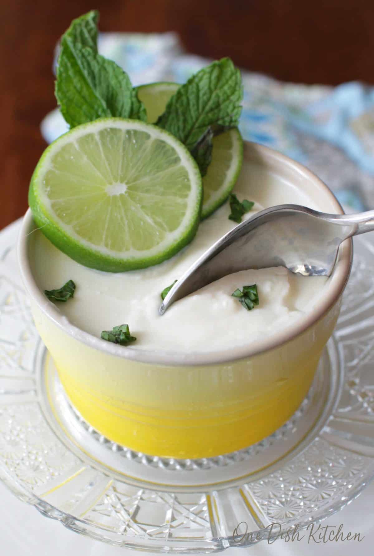 A spoonful of a lime posset topped with two lime wheels and mint leaves