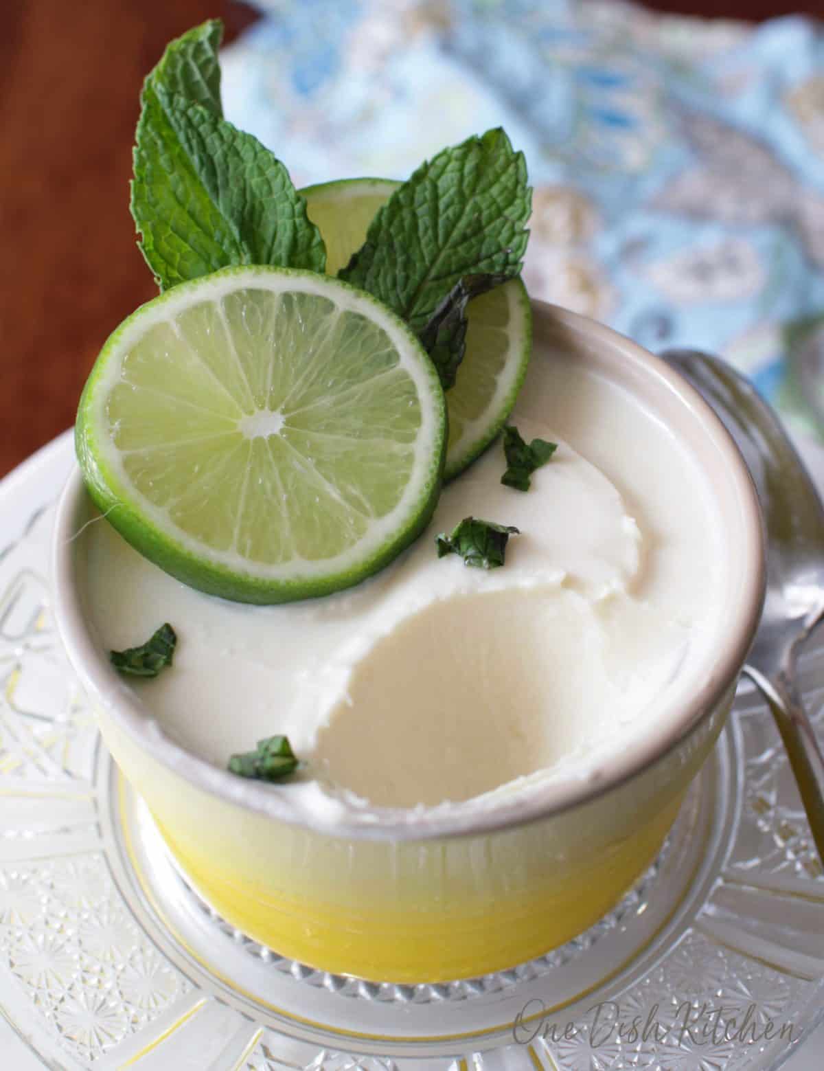 A spoonful missing of a lime posset topped with two lime wheels and mint