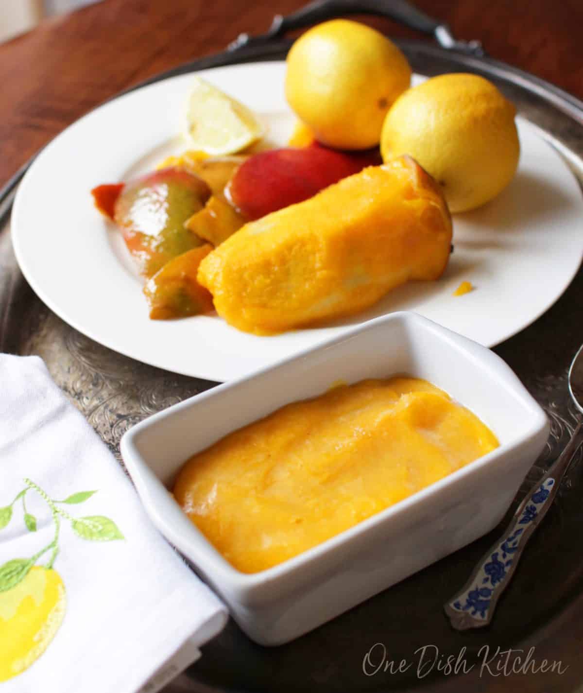 Frozen mango sorbet next to a plate of mango slices and lemons.