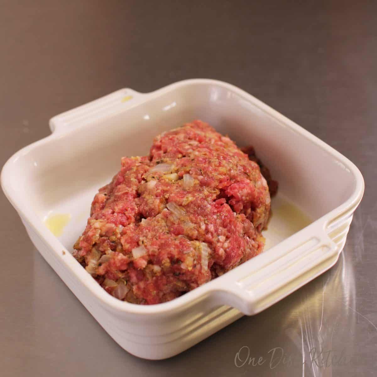 Uncooked meatloaf in a baking dish.