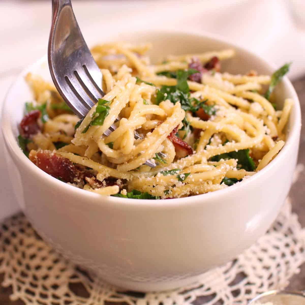 Pasta carbonara twirled around a fork from a bowl.