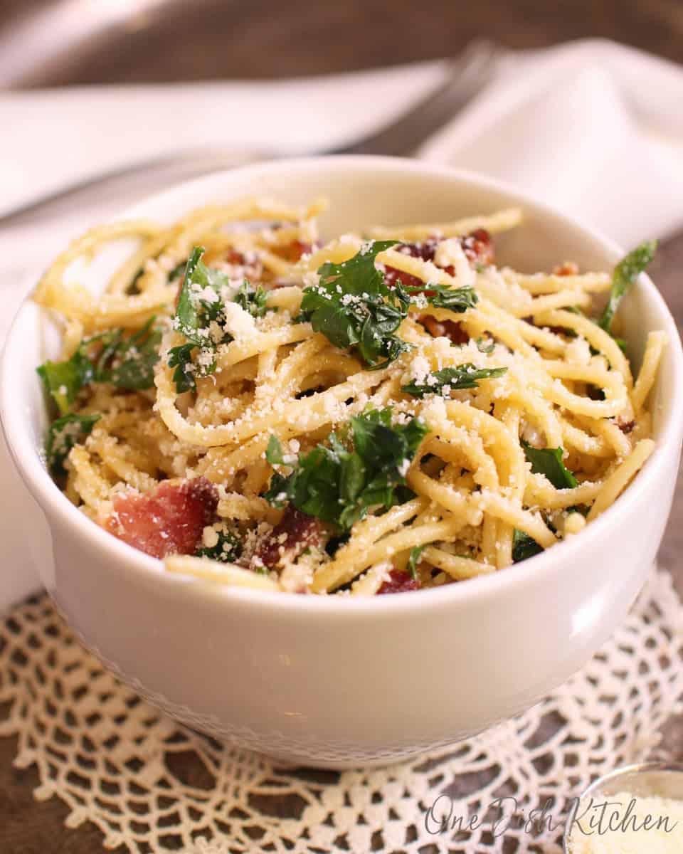 a white bowl filled with pasta carbonara.