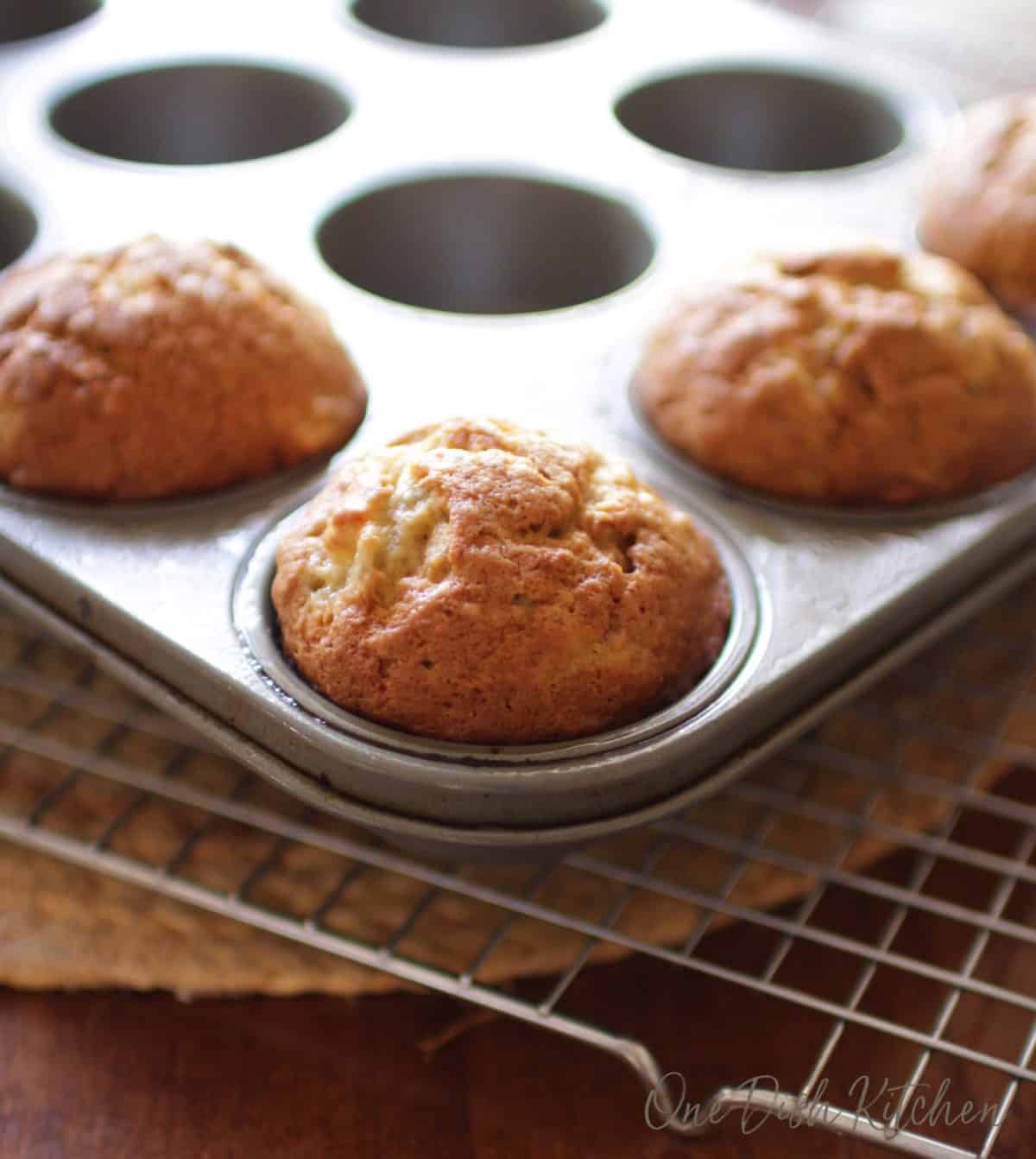 a close up of four banana muffins in a muffin tin