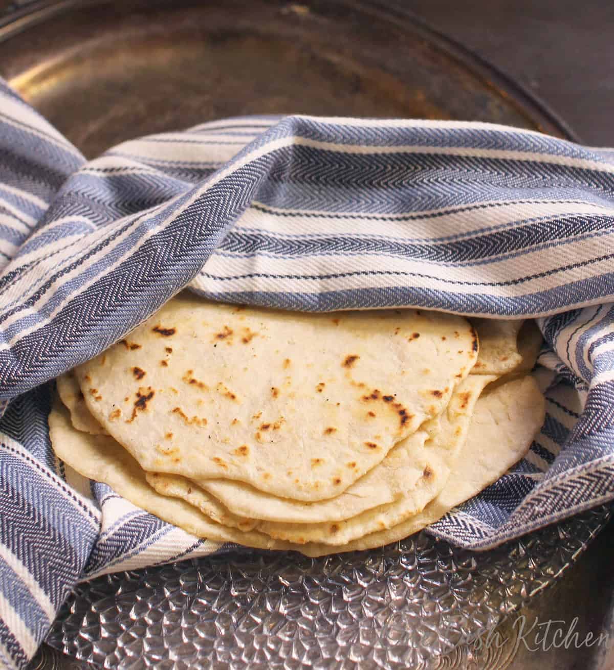 a small batch of pliable, soft flour tortillas wrapped in a towel.