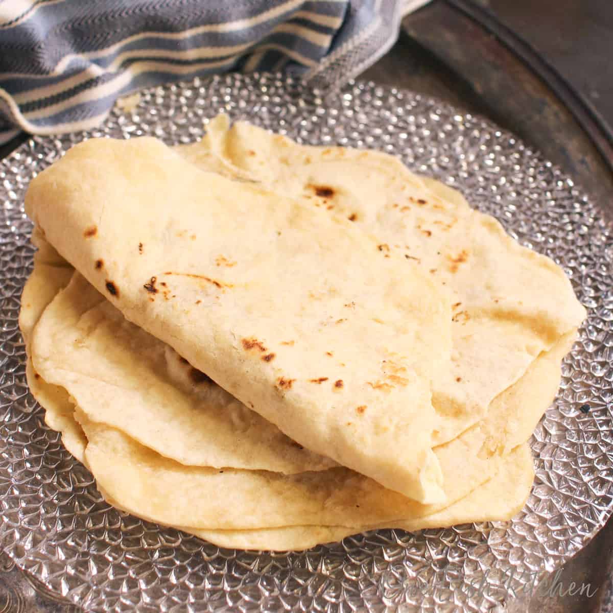 a small batch of homemade flour tortillas on a plate.
