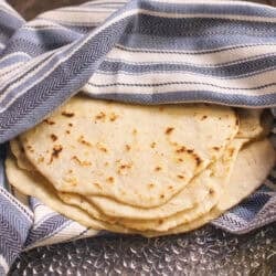 a small batch of pliable, soft flour tortillas wrapped in a towel.