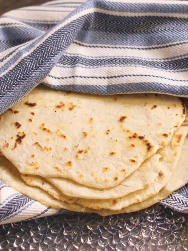 a small batch of pliable, soft flour tortillas wrapped in a towel.