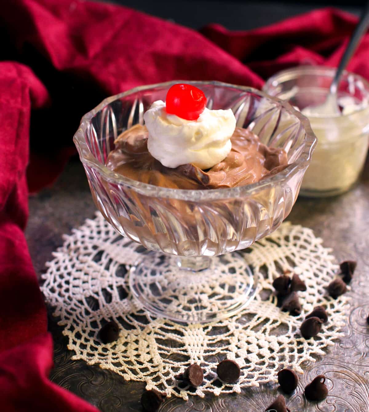 a bowl of chocolate mousse topped with whipped cream and a cherry.