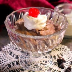 a bowl of chocolate mousse topped with whipped cream and a cherry.
