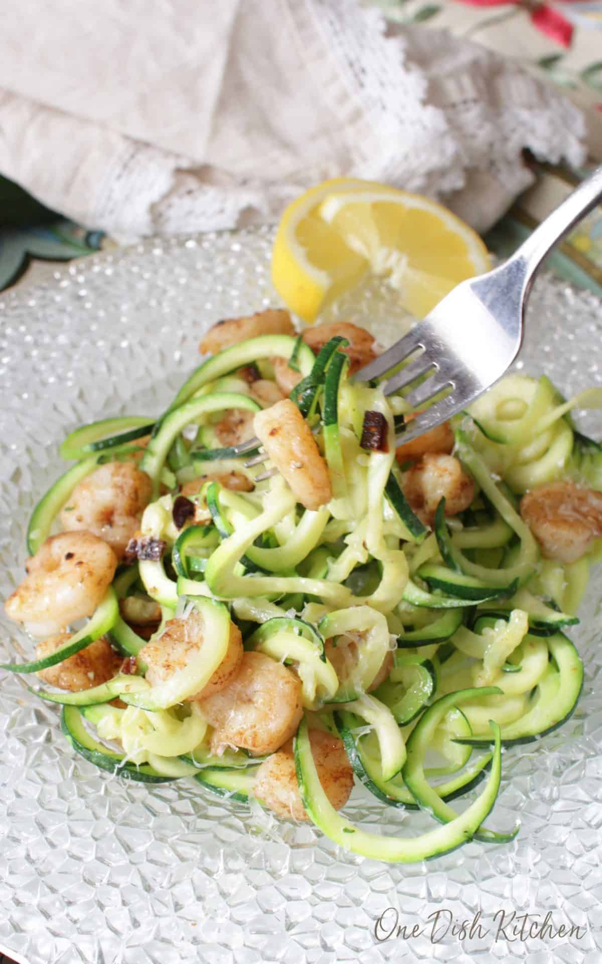A big plate of zucchini noodles with a forkful of grilled shrimp and zucchini.