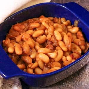 a single serving of baked beans in a blue dish on a silver tray.