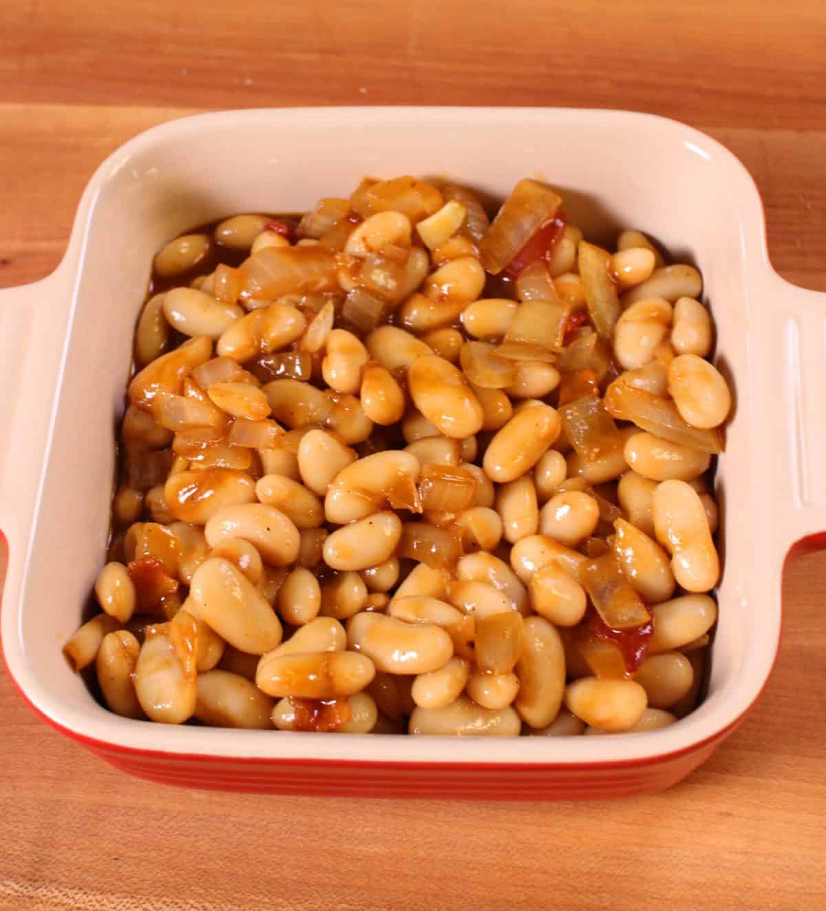 beans with sauce in a small red baking dish.