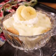 a small banana cream pie in a dessert dish next to a floral napkin