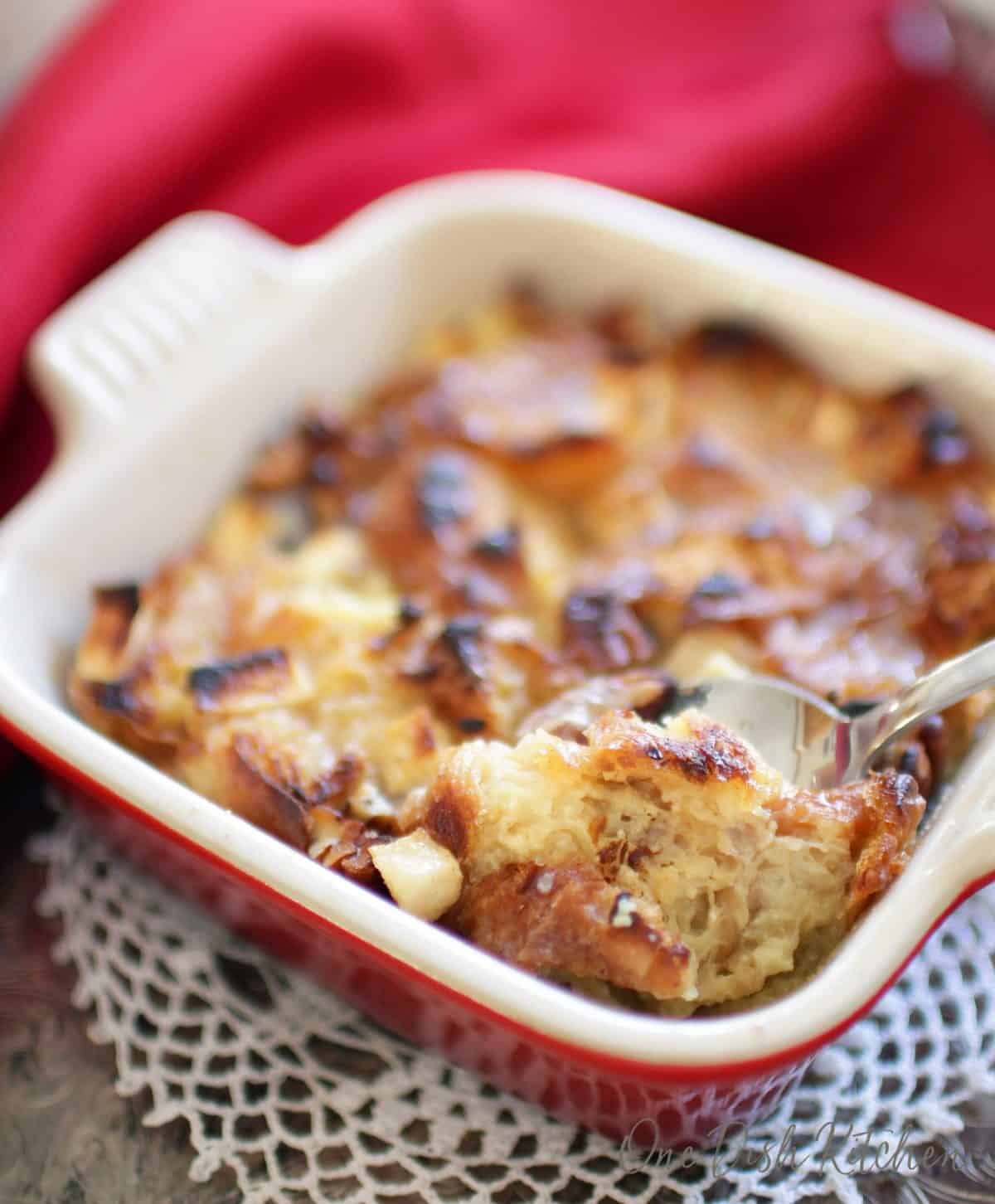 A spoonful of breakfast bread pudding from a small baking dish.