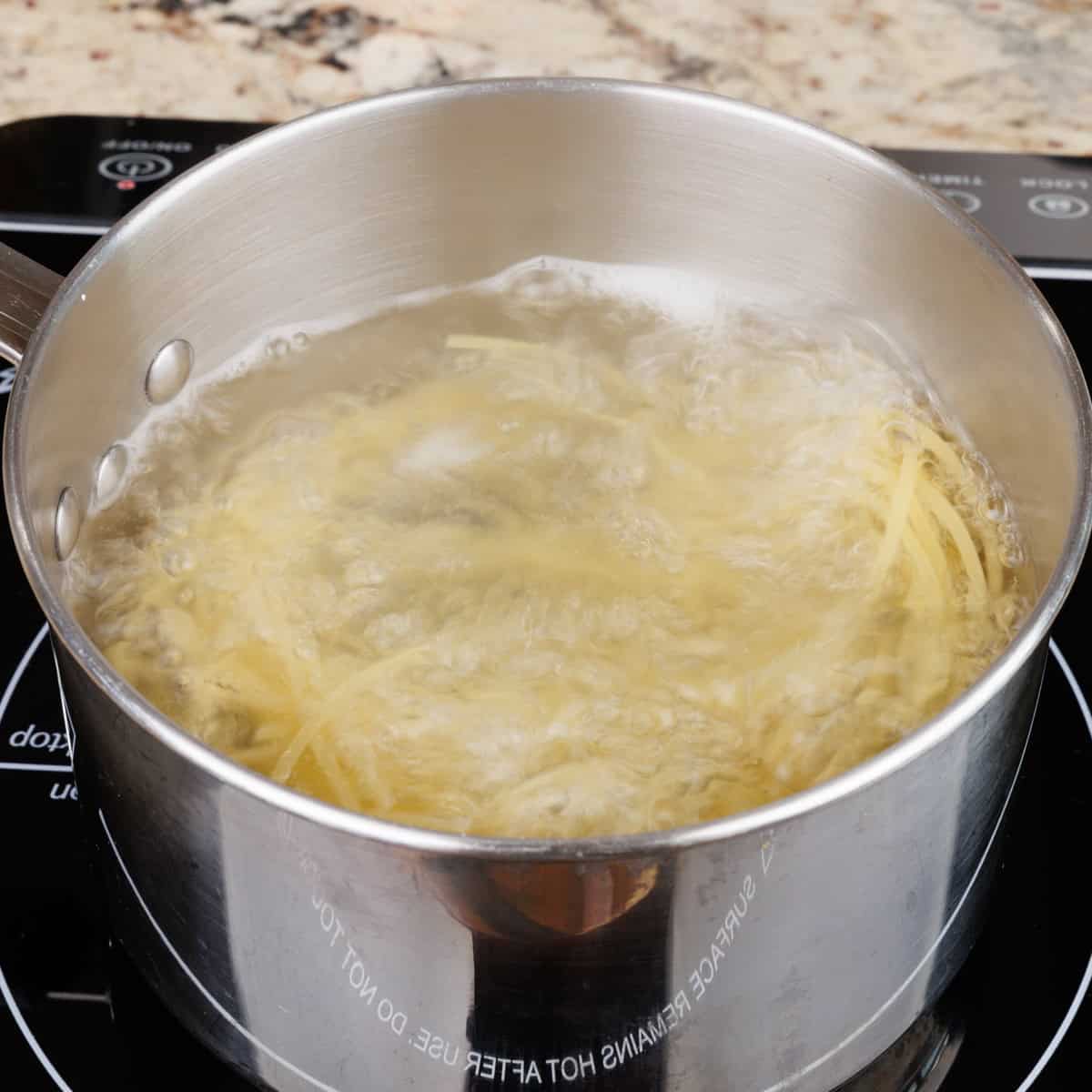 a single serving of noodles cooking in a pot on the stove.