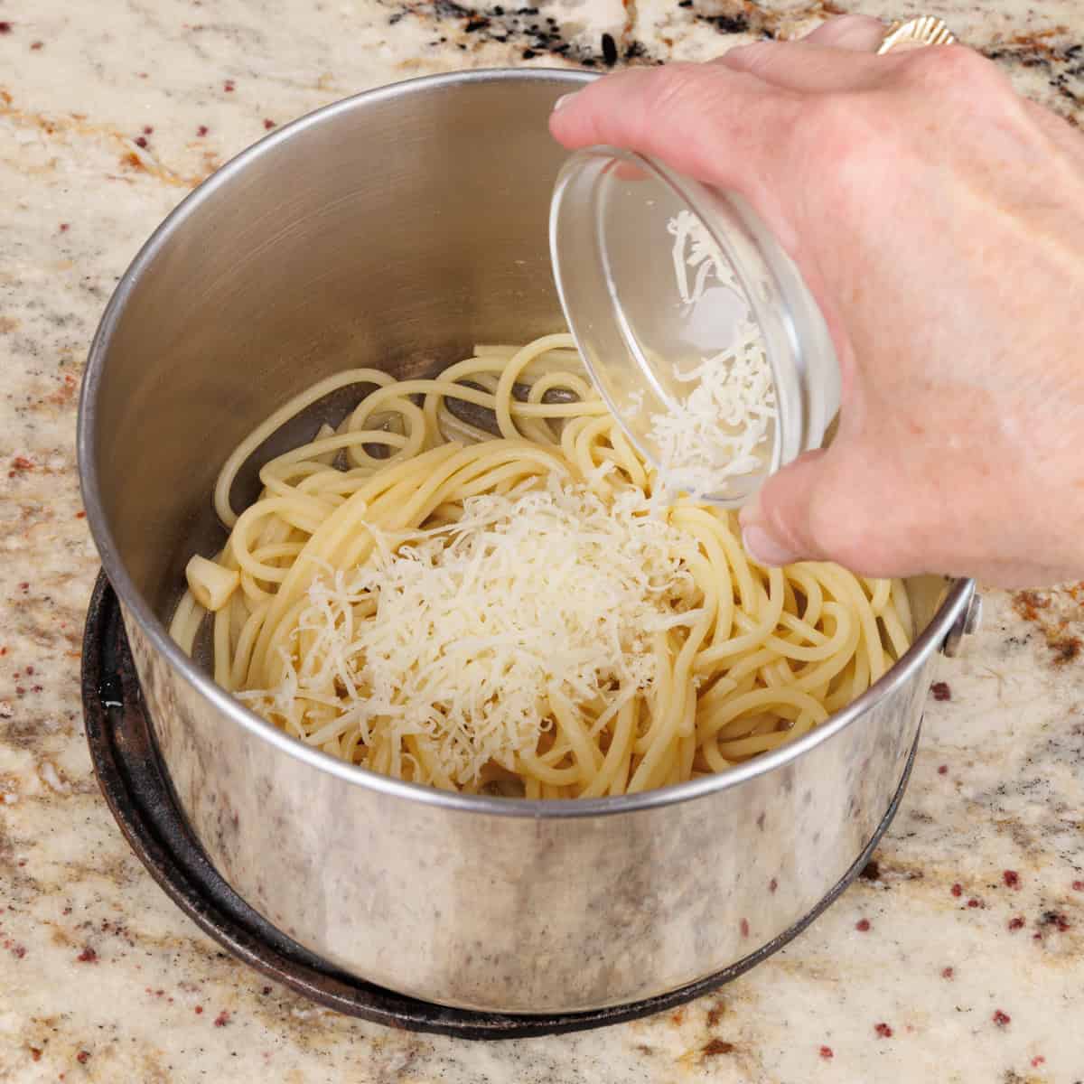 adding parmesan cheese to a bowl of pasta.