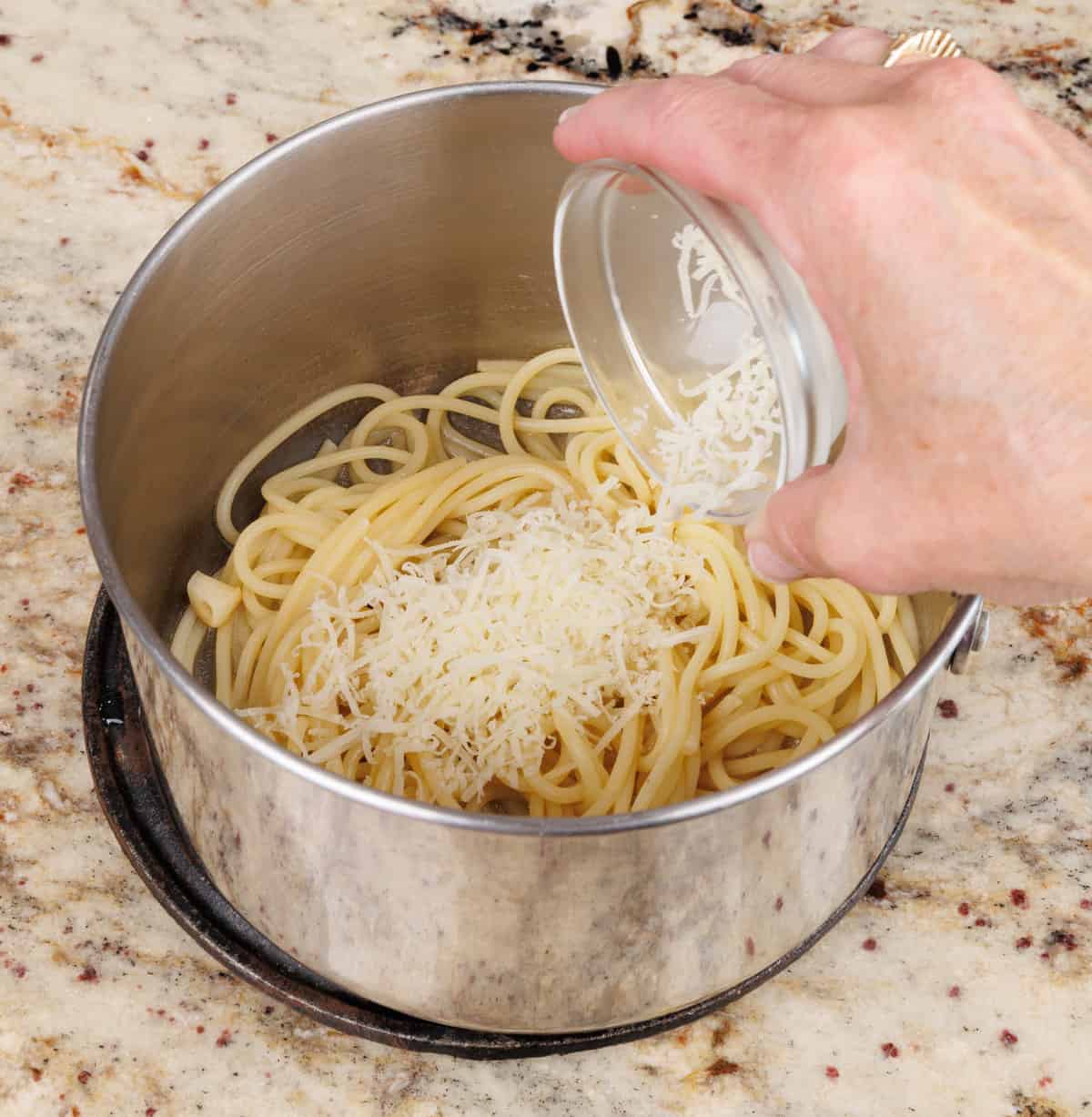 adding parmesan cheese to a bowl of pasta.