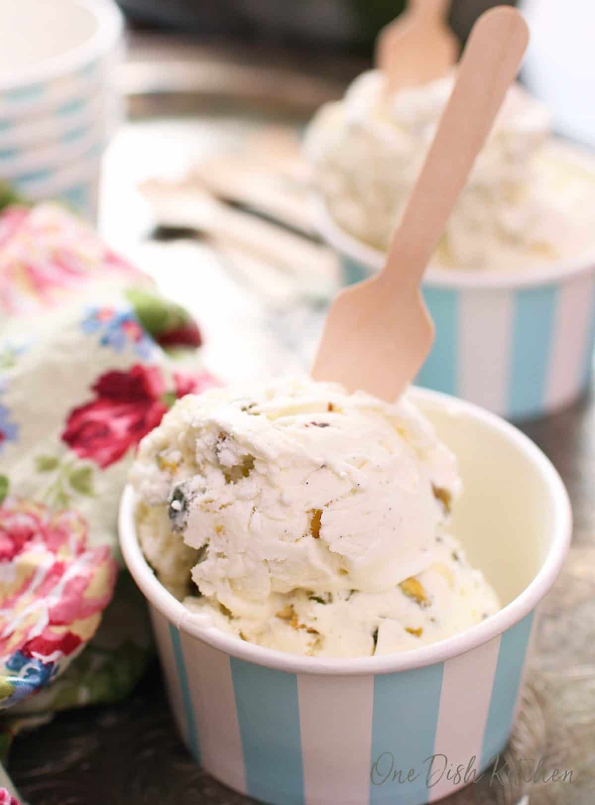 a blue and white striped cup filled with pistachio ice cream with a wooden spoon sticking out of the side.