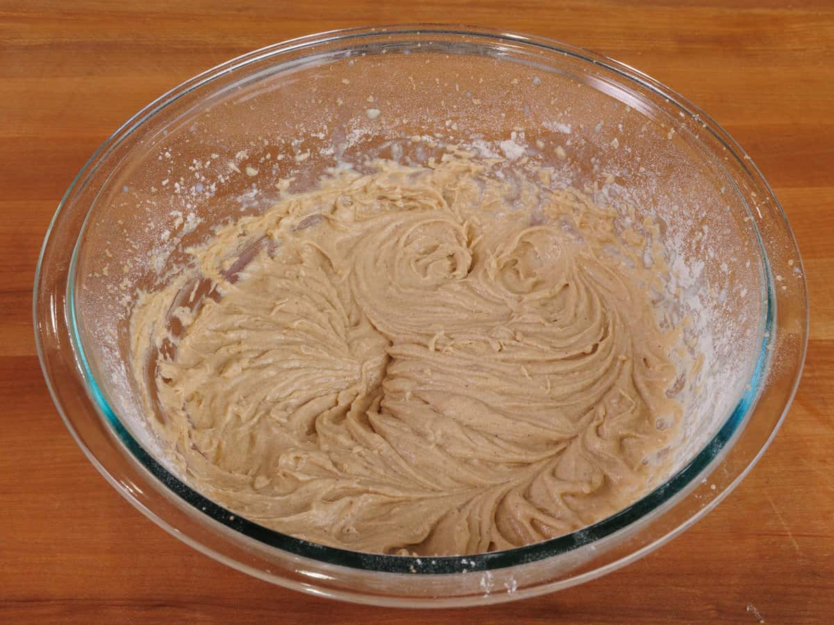 milk added to spice cake batter in a mixing bowl.