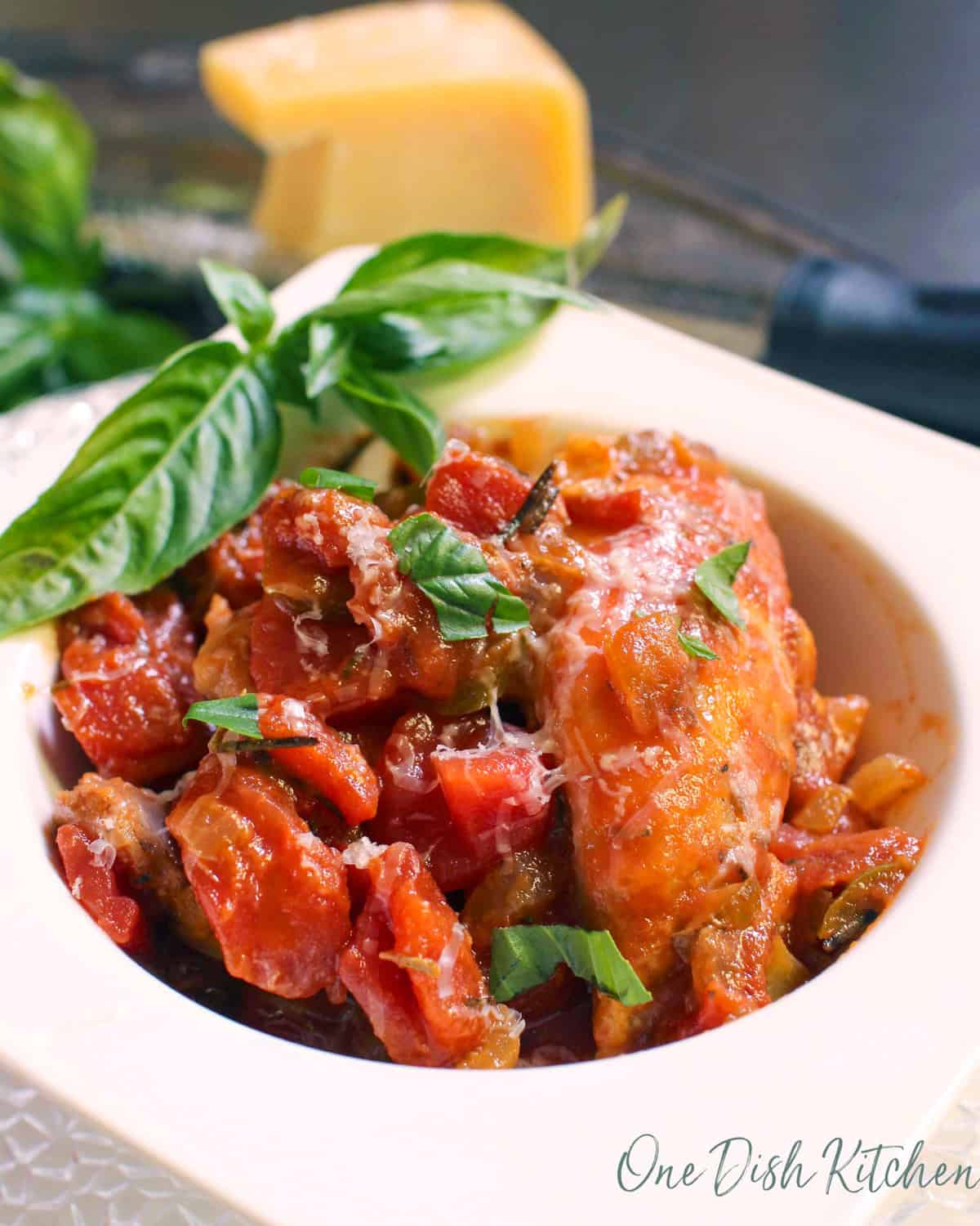 single serving chicken cacciatore with fresh basil in a white bowl.
