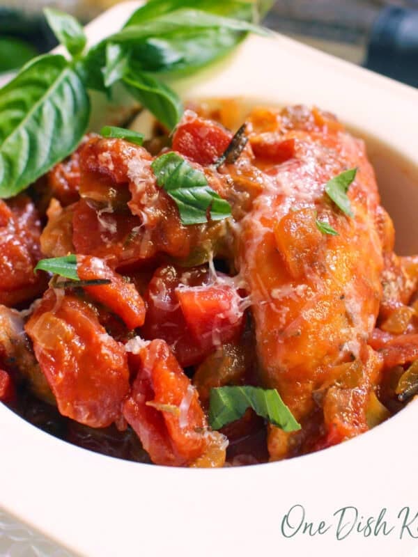 single serving chicken cacciatore with fresh basil in a white bowl.